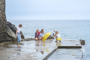 Budva, Karadağ, 06 Ekim 2018: Eğlenceli ve onların akıllı fotoğraf çekimi birbirlerinin şirket arkadaş - üç genç güzel kız - ve beş yıllık eski plajda yürüyor küçük bir kız kızlar var 