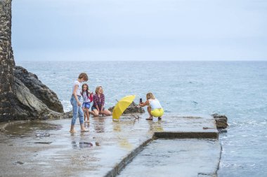 Budva, Karadağ, 06 Ekim 2018: Eğlenceli ve onların akıllı fotoğraf çekimi birbirlerinin şirket arkadaş - üç genç güzel kız - ve beş yıllık eski plajda yürüyor küçük bir kız kızlar var 