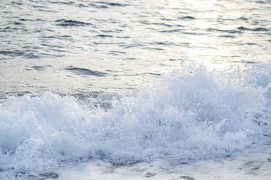 Sahil, gün batımı ışık atışında dalgalar deniz ile küçük çakıl kaplı