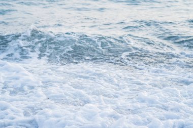 Sahil, gün batımı ışık atışında dalgalar deniz ile küçük çakıl kaplı