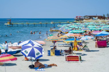 Durres, Arnavutluk, 21 Ağustos 2018: Arnavut Durres yakın şehrin waterfront şehrin ana plaj. Biz sakin masmavi deniz, kumlu bir plaj, çok sayıda renkli şemsiye ve plaj şezlong, turistler ve yerliler, bir kalabalık görmek