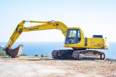 Adriyatik Denizi kıyısında inşaat alanında bir güneşli bahar gününde. Ön planda yerde kazılar bir ekskavatör ve arka planda mavi deniz görebilirsiniz