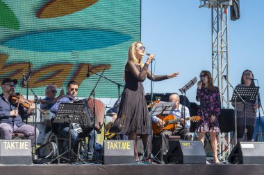 Virpazar, Karadağ, Mart, 24, 2019: karadağlı kasabasında Virpazar 'da şarap ve balıkların kamu Şenliği. Açık havada sahnede parkta, yerel bir grup gerçekleştirir-kemancı, gitarist, accordionist, vokalist ve vokalistlerden destek. Kadın günah