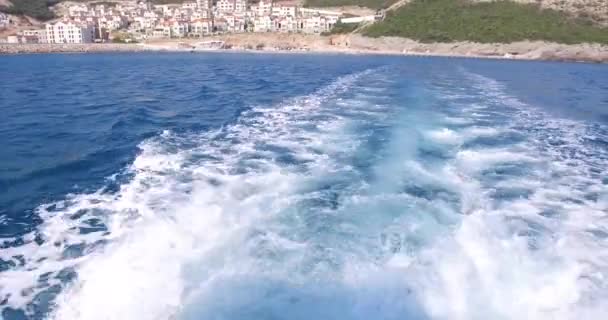 Luxusjacht segelt im Meer, große schäumende Wellen weichen vom Kiel und den Seiten der Jacht ab. Berge sind von Bord aus zu sehen — Stockvideo