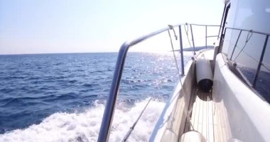 Lüks yat denize açılıyor, büyük köpüklü dalgalar yat omurgave yanlarından ayrılıyor. Dağlar tahtadan görülür