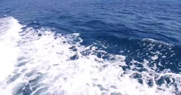 Luxusjacht segelt im Meer, große schäumende Wellen weichen vom Kiel und den Seiten der Jacht ab. Berge sind von Bord aus zu sehen — Stockvideo
