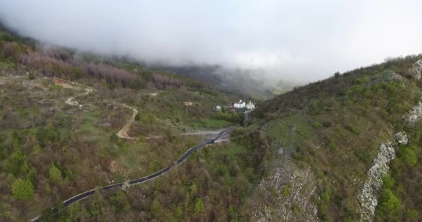 Vlucht in de wolken. Een beeld van de aarde door de wolken. Een kronkelende bergweg. De weg is op de hoogten van de heuvels van het bos. Luchtfoto — Stockvideo