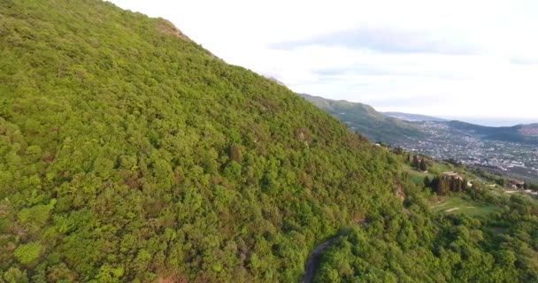 Aerial quadcopter shot van een ongerepte bossen en wegen tussen hen hoog in de bergen in Zuid-Montenegro. De zon verlicht de top van de berg — Stockvideo