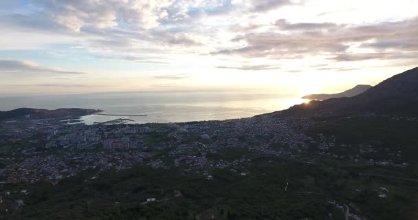 Luftaufnahme mit dem Quadrocopter von der grünen montenegrinischen Stadtbar, die an der adriatischen Küste liegt, bei Sonnenuntergang im Frühling. Berg im Hintergrund — Stockvideo