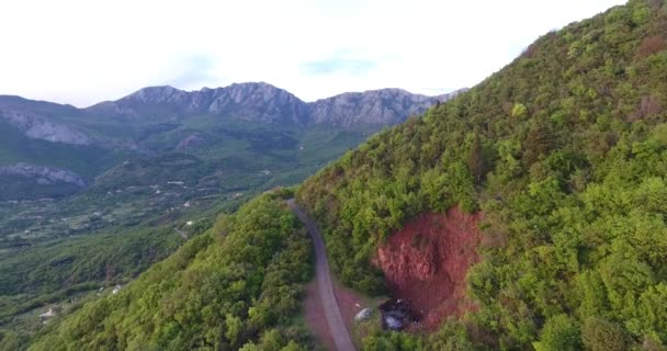 Aerial quadcopter laukaus koskematon metsät ja tiet niiden välillä korkealla vuoristossa Etelä-Montenegrossa. Aurinko valaisee vuoren huipun. — kuvapankkivideo