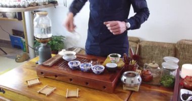 Çay dükkanında Çin çayı tadımı. Satıcı, Avrupa giymiş, tatmak için Çin çayı demler. Çin çay seti, yakın çekim geleneksel Çin çaydanlığı ve bambu paspaslar üzerinde bardak