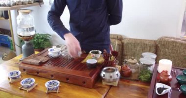 Çay dükkanında Çin çayı tadımı. Satıcı, Avrupa giymiş, tatmak için Çin çayı demler. Çin çay seti, yakın çekim geleneksel Çin çaydanlığı ve bambu paspaslar üzerinde bardak