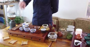 Çay dükkanında Çin çayı tadımı. Satıcı, Avrupa giymiş, tatmak için Çin çayı demler. Çin çay seti, yakın çekim geleneksel Çin çaydanlığı ve bambu paspaslar üzerinde bardak