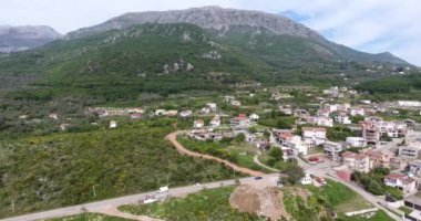 Dağ vadisinde quadcopter uçuşu. Yeşil alanların, küçük bir köyün çatılarının ve sarma yollarının görünümü