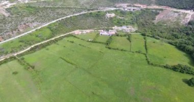 Dağ vadisinde quadcopter uçuşu. Yeşil alanların görünümü, küçük bir köyün çatıları ve yolda seyahat eden araba ve diğer ulaşım ile sarma yolları