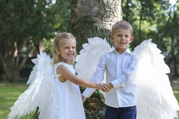 Anak-anak berpakaian seperti malaikat berjalan di taman Stok Gambar