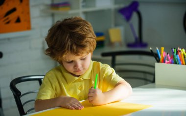 Okula dönelim. Sınıfta masa başında oturan sevimli okul çocuğu çiziyor ya da notlar yazıyor. Konsantre küçük öğrenci ilkokul için ödev yazıyor. İlkokul için ödev yapan küçük bir çocuk.