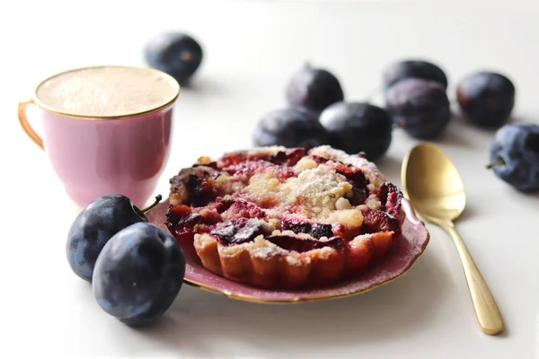Plum cake and a cup of coffee surrounded with fresh plums. Styled stock photo