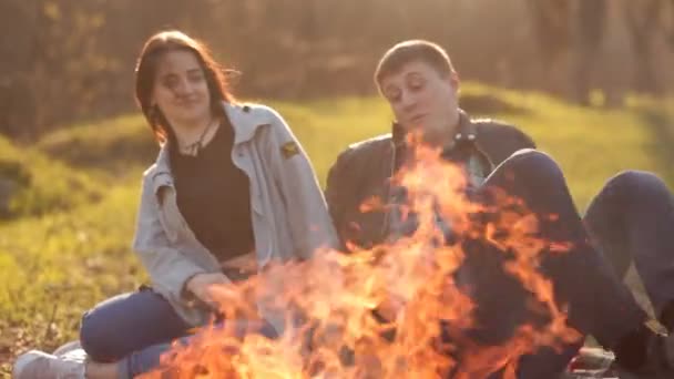 A pair of lovers sit together near a fire in nature. Romantic pastime — Stock Video