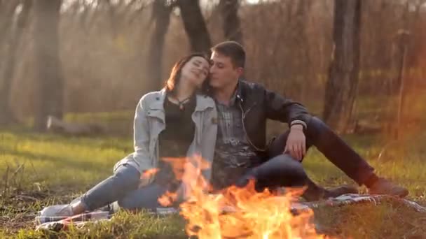 Пара влюблённых сидят рядом с огнём в природе. Романтическое развлечение — стоковое видео