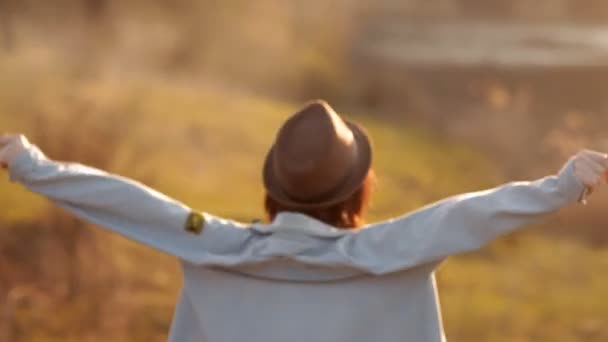 A menina desce da colina para o namorado, de pé perto do lago. Um casal amoroso passa o tempo juntos durante o pôr do sol — Vídeo de Stock