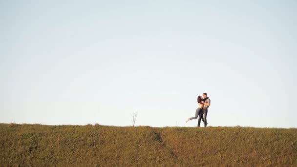 Un tipo dando vueltas a su novia, estando en una colina, en un día soleado. Pasar tiempo juntos en la naturaleza — Vídeos de Stock