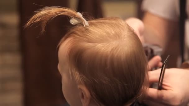 Em um cabeleireiro brutal, uma criança está sendo cortada por um cortador de cabelo — Vídeo de Stock