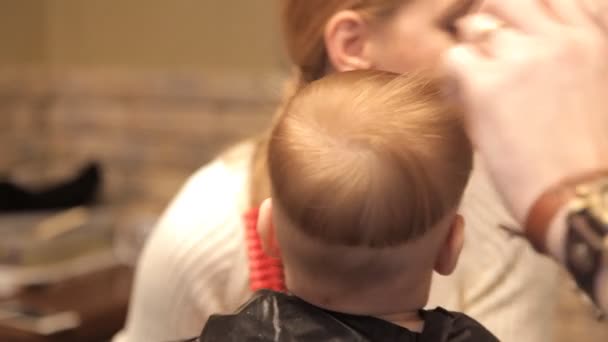 Маленька дитина порізала волосся в жорстокому чоловічому перукарні — стокове відео