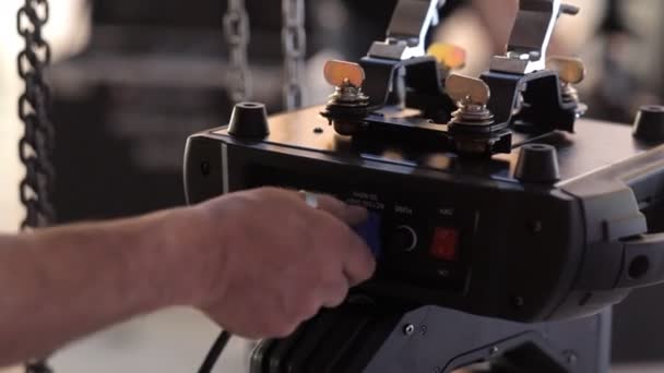 De technicus sluit de draad aan het middelpunt van de belangstelling voor de verlichting van het werkgebied in de zaal voor de viering — Stockvideo