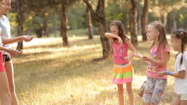 An einem sonnigen Sommertag verbringen die Kinder Zeit auf der Liegewiese, sie werden mit buntem Sand überschüttet. Kinderfreuden. Regenbogen — Stockvideo