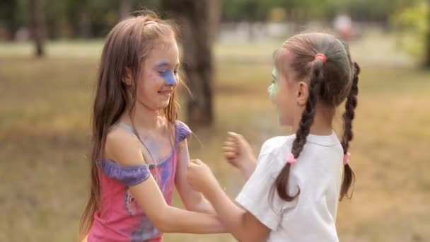 Dos niñas se están divirtiendo en un parque de recreo. Los niños se lanzan unos a otros un polvo de color holi — Vídeos de Stock