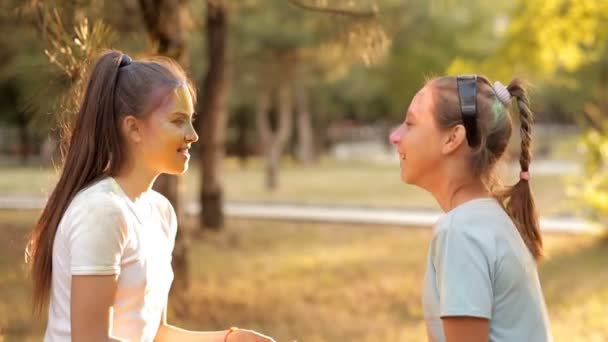 Los niños se divierten en el parque de recreación, lanzando polvo de colores holi. Los niños descansan en el tiempo soleado — Vídeos de Stock