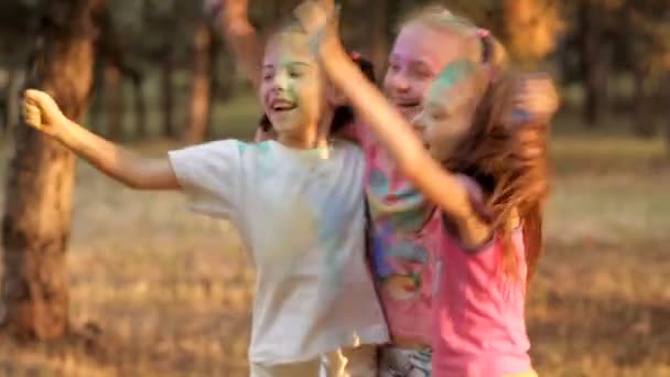 Діти розважаються в парку відпочинку, кидаючи кольорові порошкові холи. Дитячий відпочинок в сонячну погоду — стокове відео