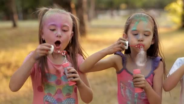Kinder vergnügen sich im Freizeitpark und blasen Blasen. Kinderanimation im Park bei sonnigem Wetter. Kinder lächeln, Freude. Holi-Fest