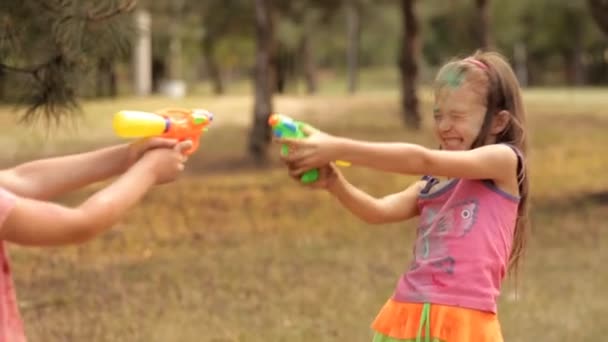 Im Freizeitpark spritzen Kinder aus einer Wasserpistole ineinander. Sommervergnügen im Freizeitpark. Freude, Lächeln der Kinder — Stockvideo