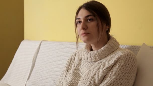 Uma jovem menina em uma camisola quente aconchegante em uma noite de inverno em casa bebendo chá e pensando em algo — Vídeo de Stock