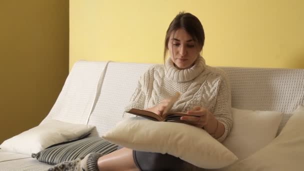 Jong meisje in gezellige warme trui op winteravond thuis, boek lezen — Stockvideo