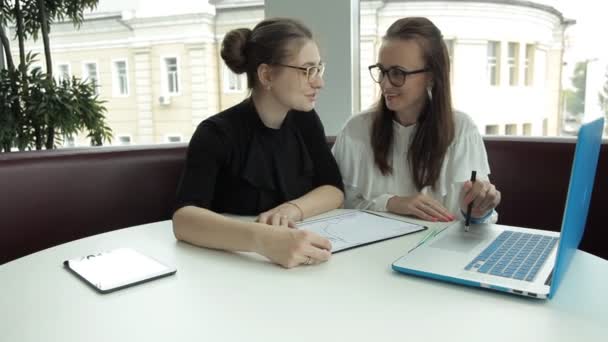 Zwei Mädchen sitzen in einem Café, diskutieren Geschäftsideen und bringen ihnen Lunchnudeln — Stockvideo