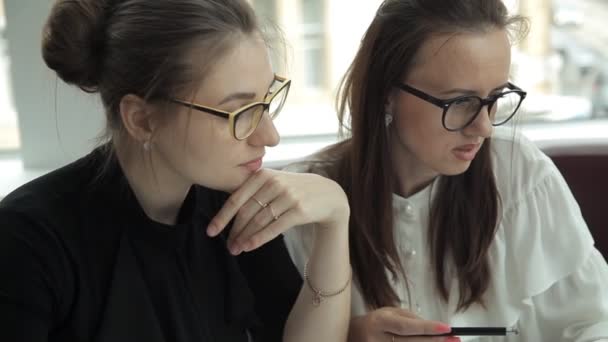 Duas garotas se sentam em um café, discutem ideias de negócios e trazem macarrão para almoçar — Vídeo de Stock