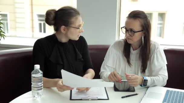 Duas meninas de negócios de óculos discutem ideias de negócios e assinam um contrato. Trabalho, tablet, laptop, negócios — Vídeo de Stock