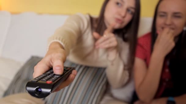 Due giovani ragazze si siedono a casa sul divano, in una giornata di pioggia guardando una commedia, parlando e ridendo. Sera, casa, comfort, divertimento — Video Stock