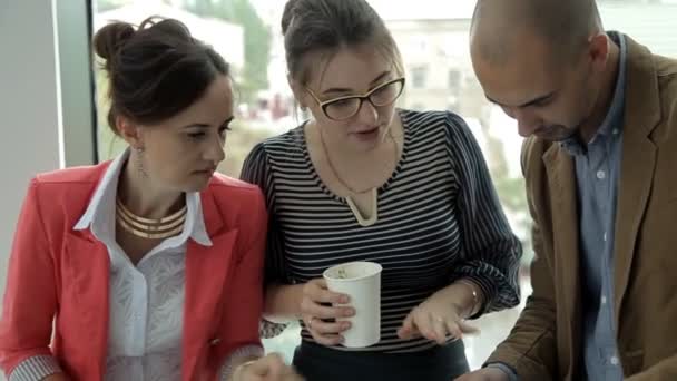 Twee jonge bedrijf meisjes en een jonge zakenman in een business center op lunch noedels eten in vakken en bespreken van bedrijfsontwikkeling — Stockvideo