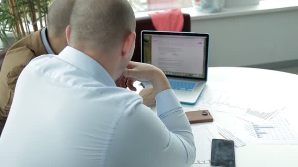 Zwei Geschäftsleute sitzen an einem Laptop und verfolgen die Geschäftsentwicklung. Unternehmen — Stockvideo