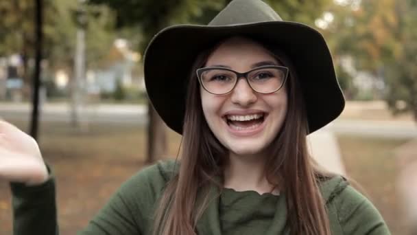 Une fille joyeuse dans le parc en automne. Emotion, une fille avec un chapeau et des lunettes — Video