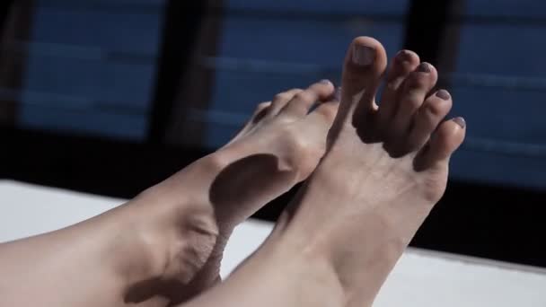 Young girl resting on the terrace overlooking the sea in summer and waving her legs — Stock Video