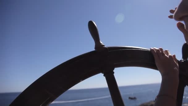 The girl rotates the steering wheel of the ship with a sea view — Stock Video