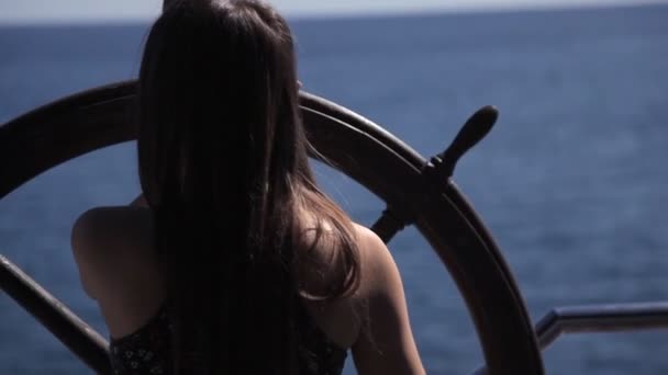 Ein junges Mädchen steht am Steuer auf der Terrasse mit Blick auf das Meer — Stockvideo