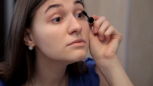 Una chica joven se prepara para una cena romántica y hace maquillaje, dibuja ojos rímel — Vídeos de Stock