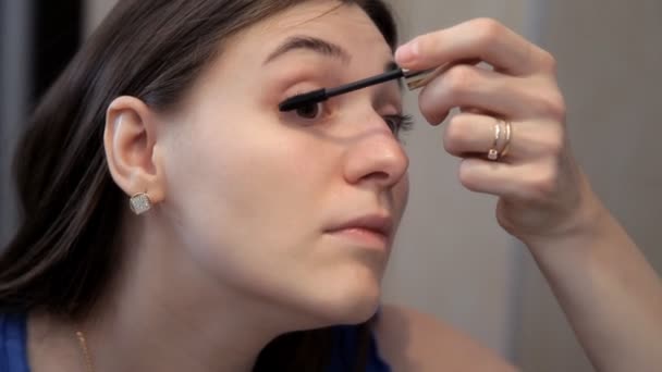 Una chica joven se prepara para una cena romántica y hace maquillaje, dibuja ojos rímel — Vídeo de stock