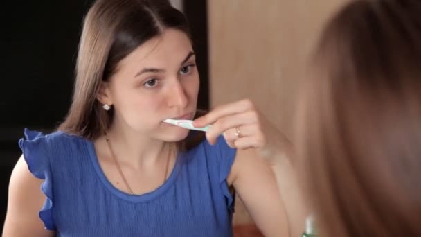 Mladá dívka tančí před zrcadlem v koupelně a čistí zuby. Bílé zuby — Stock video